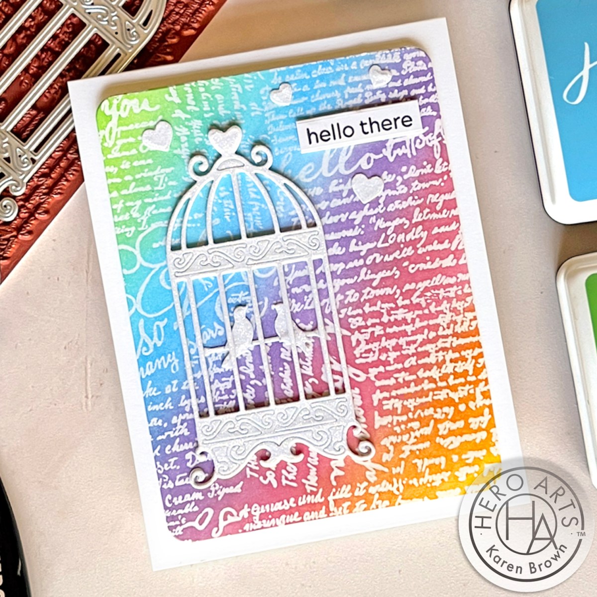 White vintage die cut bird cage on a bright rainbow colored background.