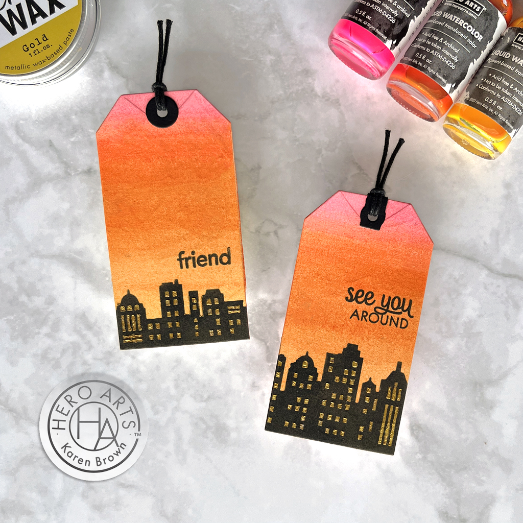 Colorful DIY tags simulating a Sunset over a cityscape created with liquid watercolors, a stencil and Hero Gold Wax.