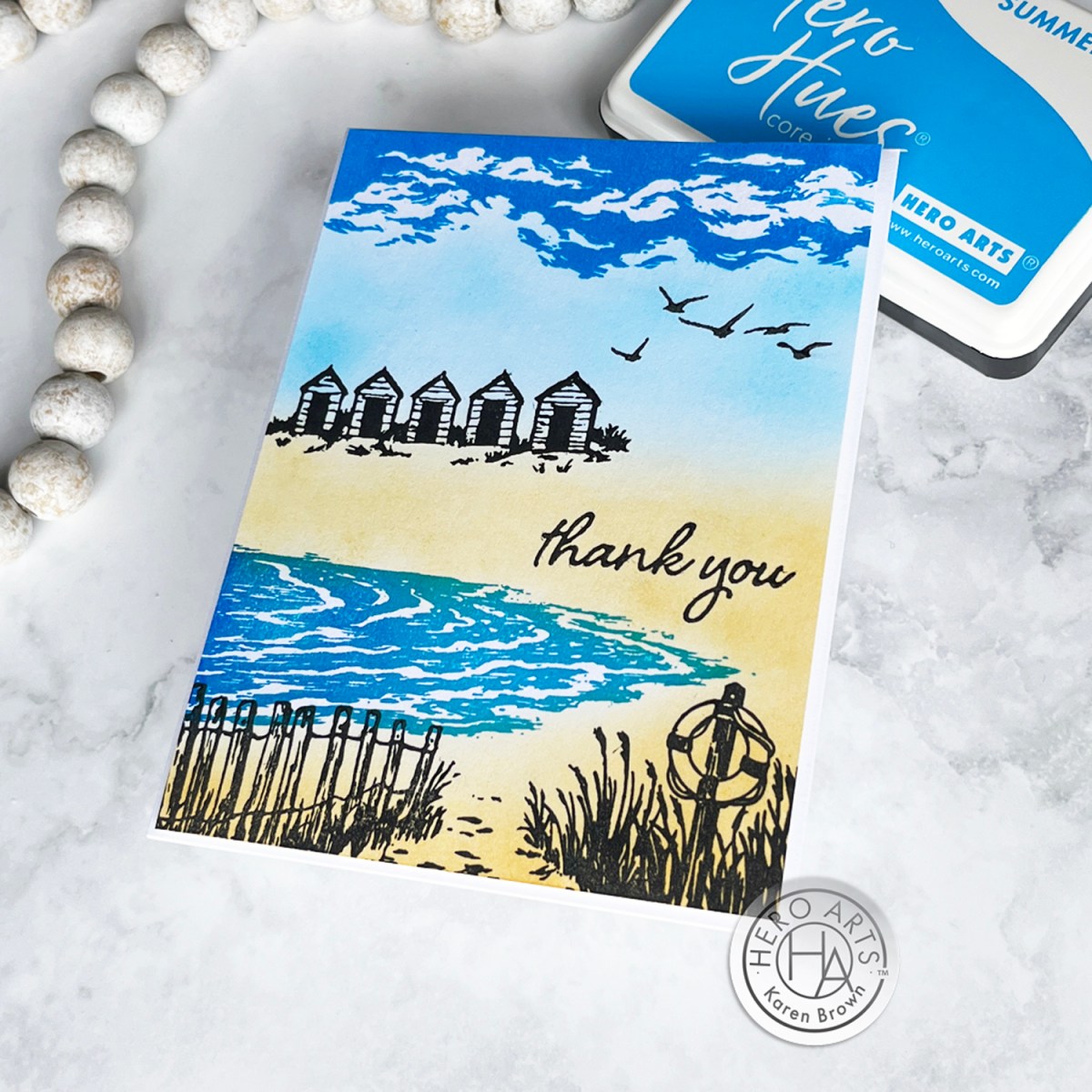 Heroscape Beach Scene handmade card with silhouette stamped fence, grass, cabanas and birds.