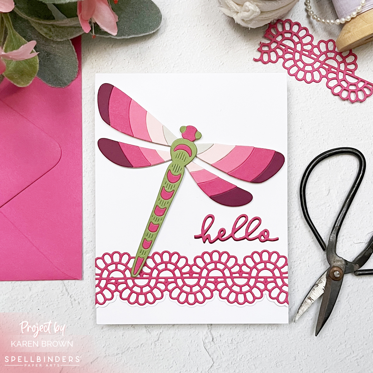 A bright and cheerful handmade card featuring a die-cut dragonfly in gradient shades of pink and green, paired with a scripty “hello” and a Scallop Eyelet Border.