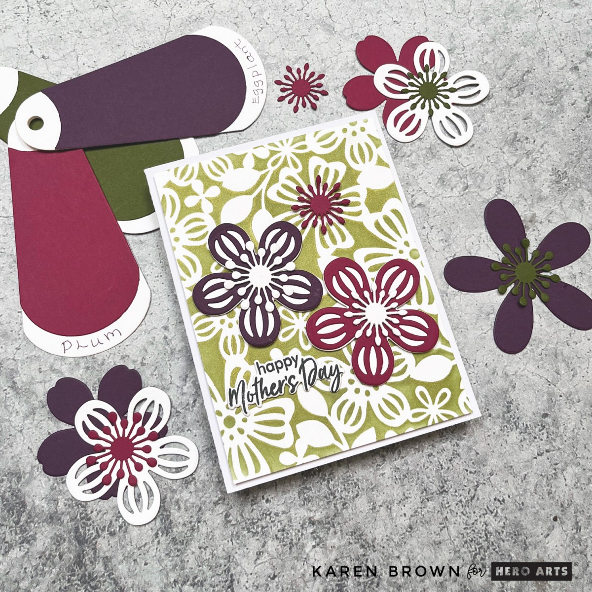 A Mother’s Day card with a rich plum and eggplant stenciled background, adorned with delicate die-cut flowers in shades of plum, eggplant, and white.