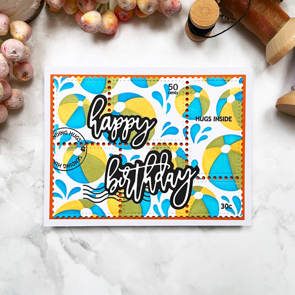A vibrant beach-themed birthday card featuring stenciled beach balls in yellow, green, and blue with a touch of shimmer.