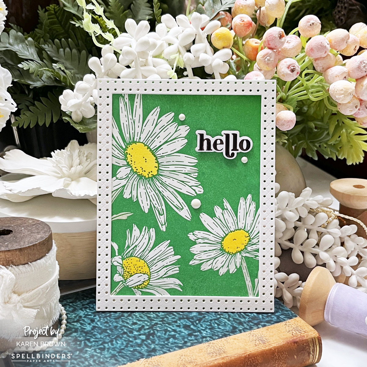A high-contrast BetterPress letterpress card with white daisies, Leaf Green inked background, and a foiled black "Hello" sentiment. Framed in white with three enamel dots.