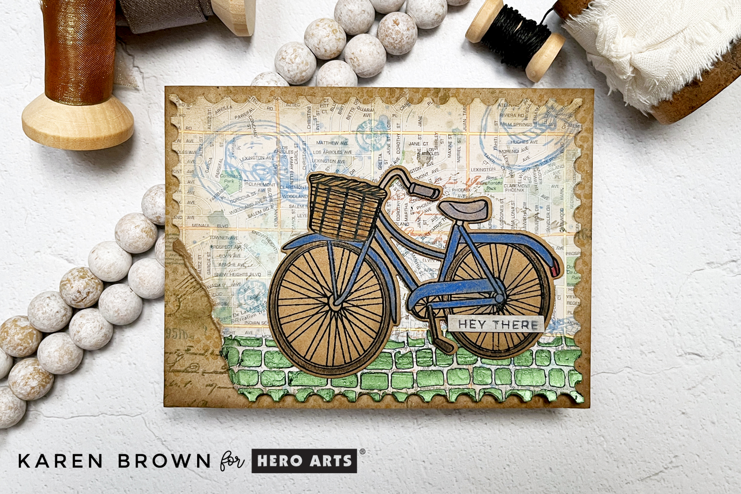A mixed media card featuring the June 2025 Hero Studio card kit bike and hat stamps.