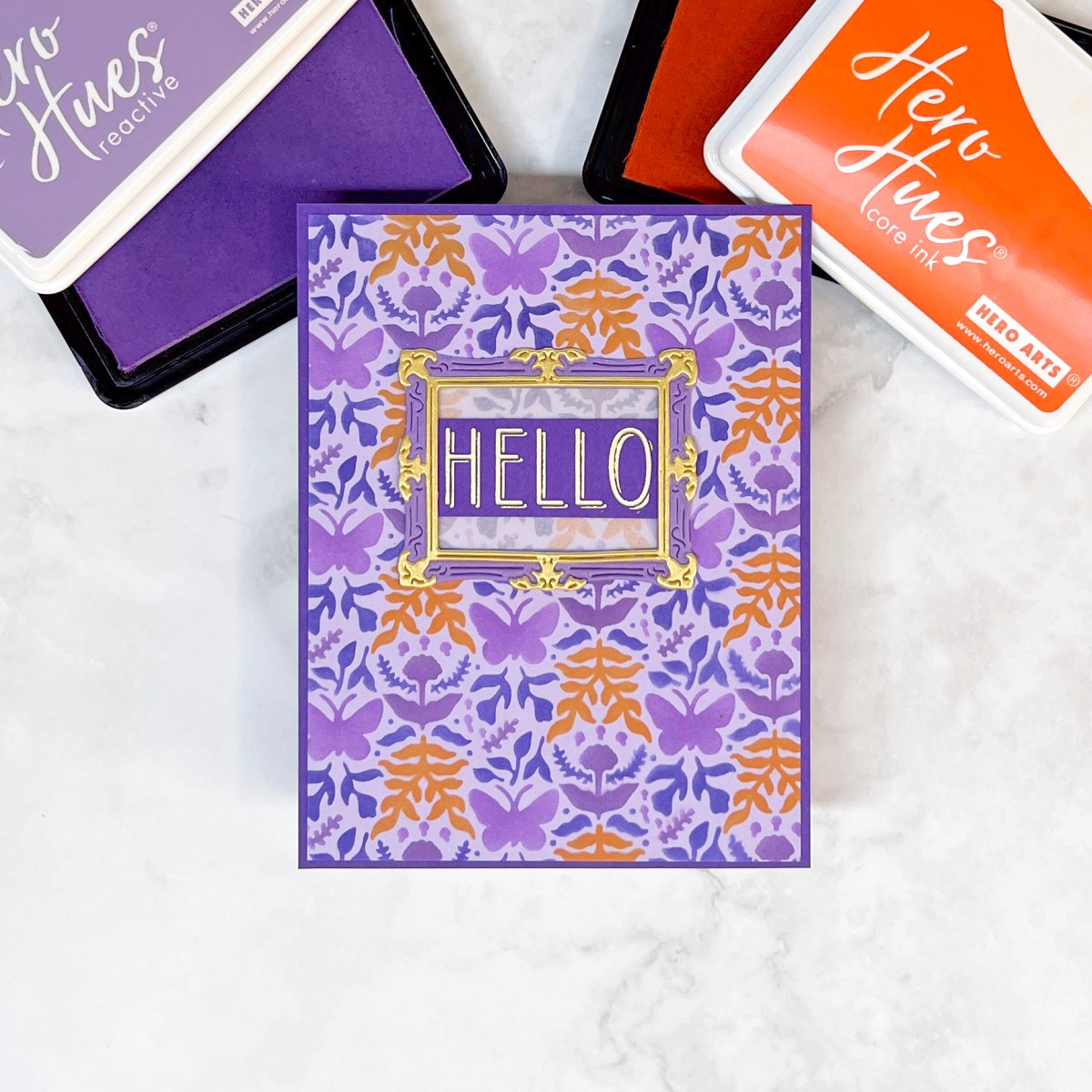 Hero Studio August 2025 Sunnyside Manor layered stencil card in 4 shades of purple + orange.