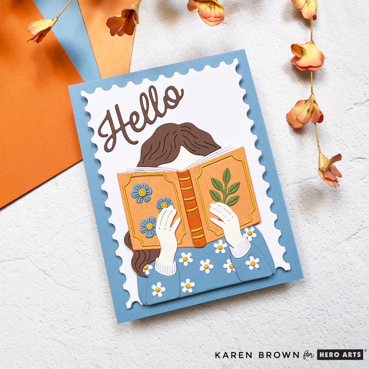 Die-cut handmade scene card featuring a girl reading a book framed with a postage stamp border and scripty hello sentiment