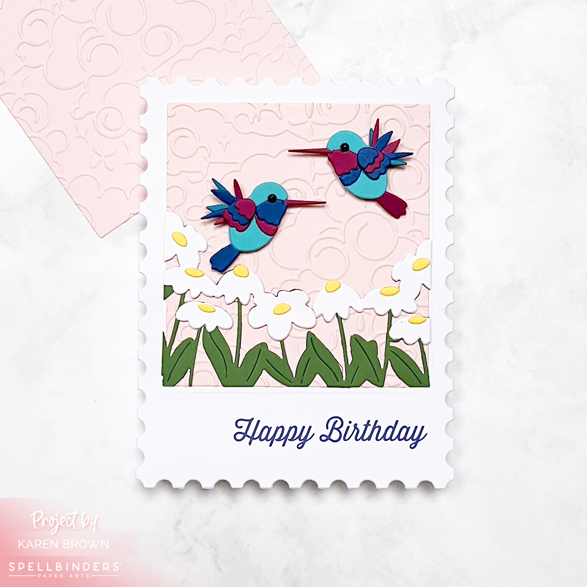 Cute die cut card with  hummingbirds hovering over a daisy floral garden. 