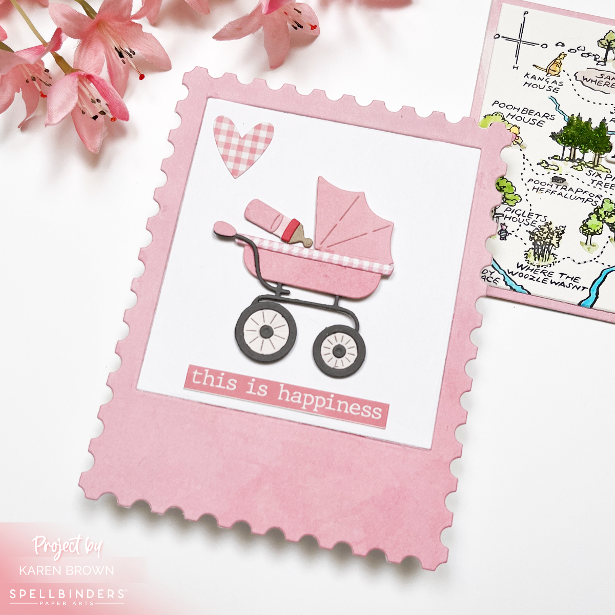Pink baby shower card with a die-cut stroller, postage-style background created with the Spellbinders January 2026 Large Die of the Month, and vintage-inspired embellishments.