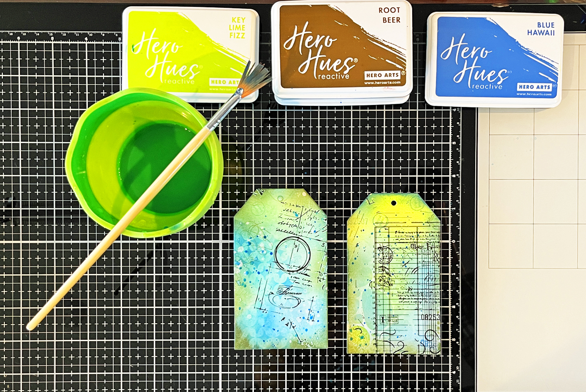 Process photo showing water splatters and ink splatters on my in-process mixed media art tag. 