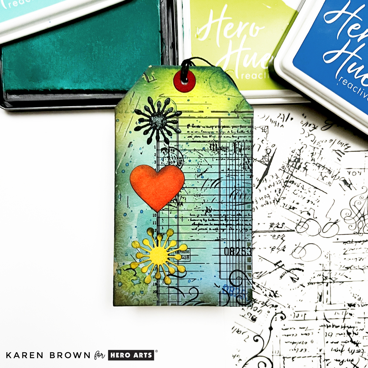 Colorful ledger style mixed media tag with die cut floral sunbursts and a cheerful orange heart.