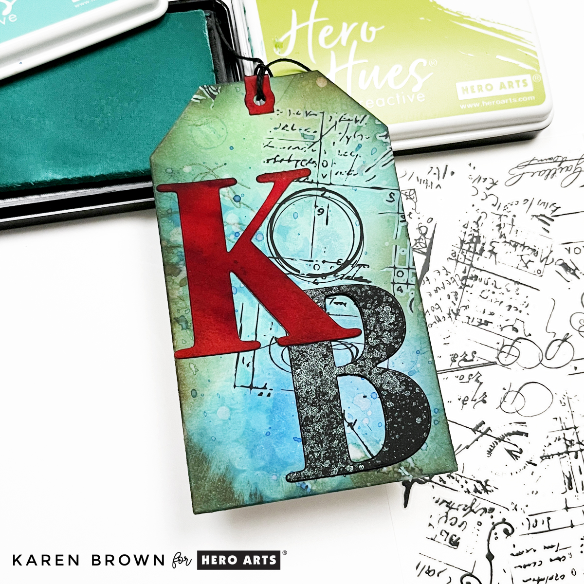 Close-up of my aqua blue mixed media tag with personalized die cut initials (KB) and Hero Arts rub-on Hero Transfers. 