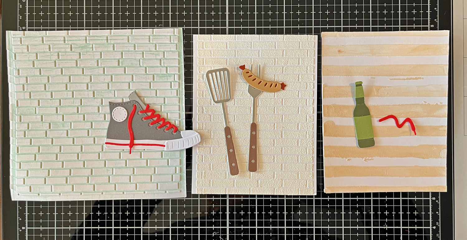 Premade embossed background panels auditioned behind die cut elements for scene card design, two brick backgrounds and one tan stripe.