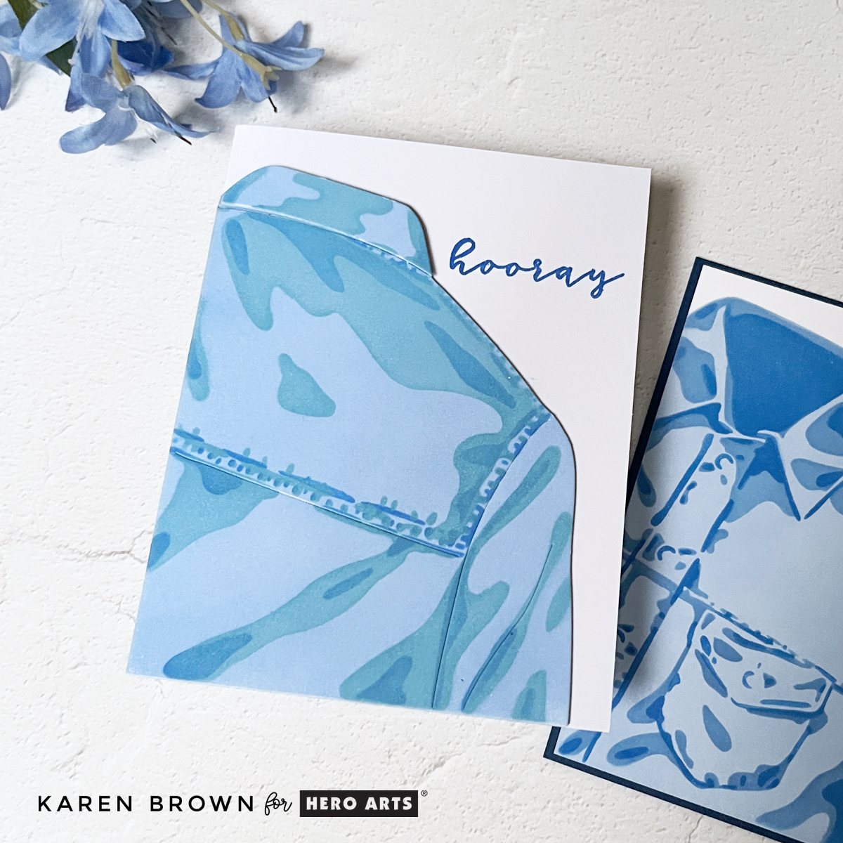 Layered die cut jean jacket card stenciled in soft blue tones, stacked for dimension and adhered to a white A2 card base.