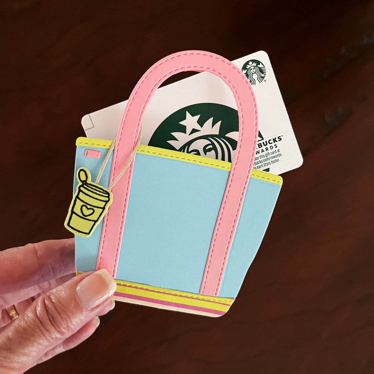 Tote bag holding a gift card, styled as a decorative papercraft gift