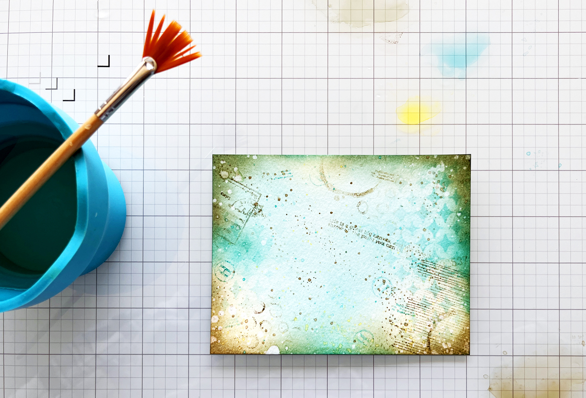 Adding water splatters and ink splatters to a mixed media card background.