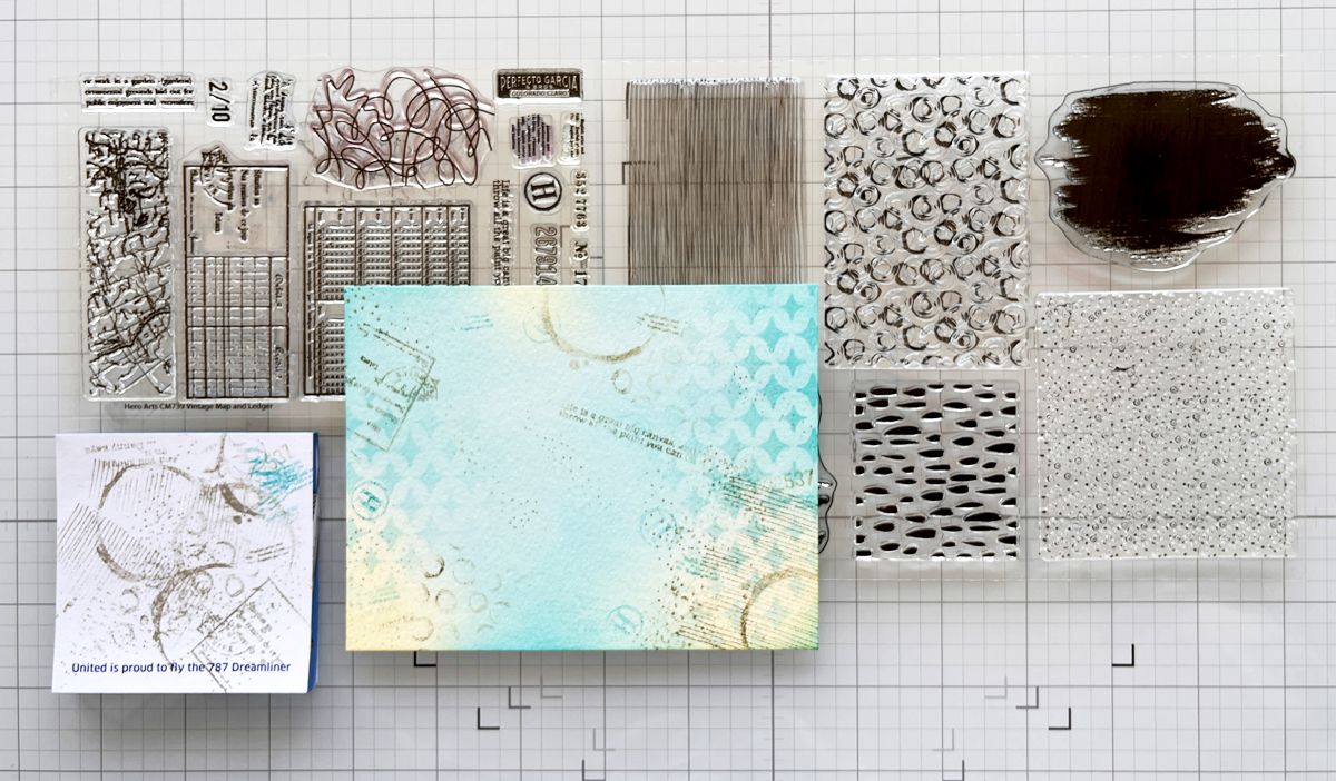 Stamping layers on a mixed media card background.