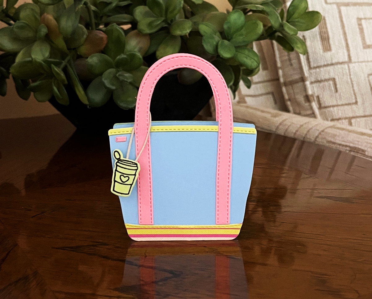 Die-cut dimensional tote bag in blue and pink with a coffee charm, standing upright on a white surface