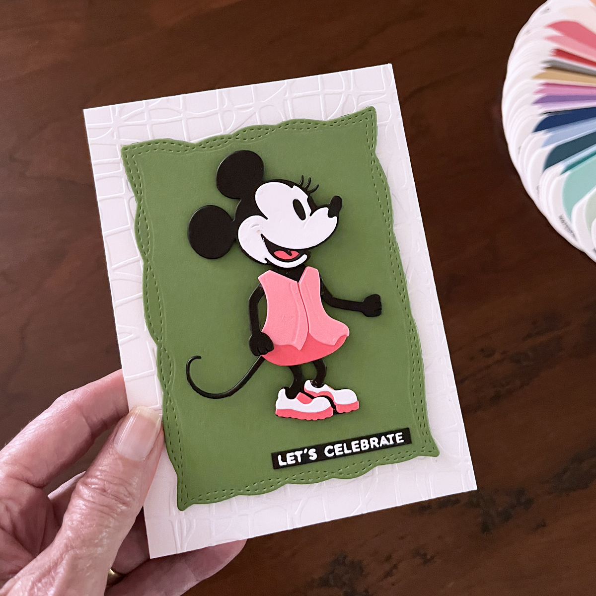 Minnie-inspired die cut birthday card with pink dress, black and white details, and green stitched mat background