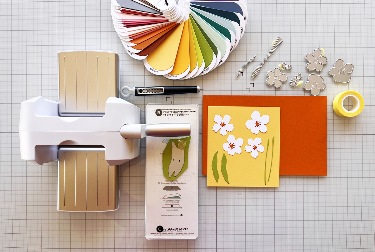Craft desk process photo showing Scout desktop die cutting machine, cardstock, die cuts, and color swatches during cardmaking.