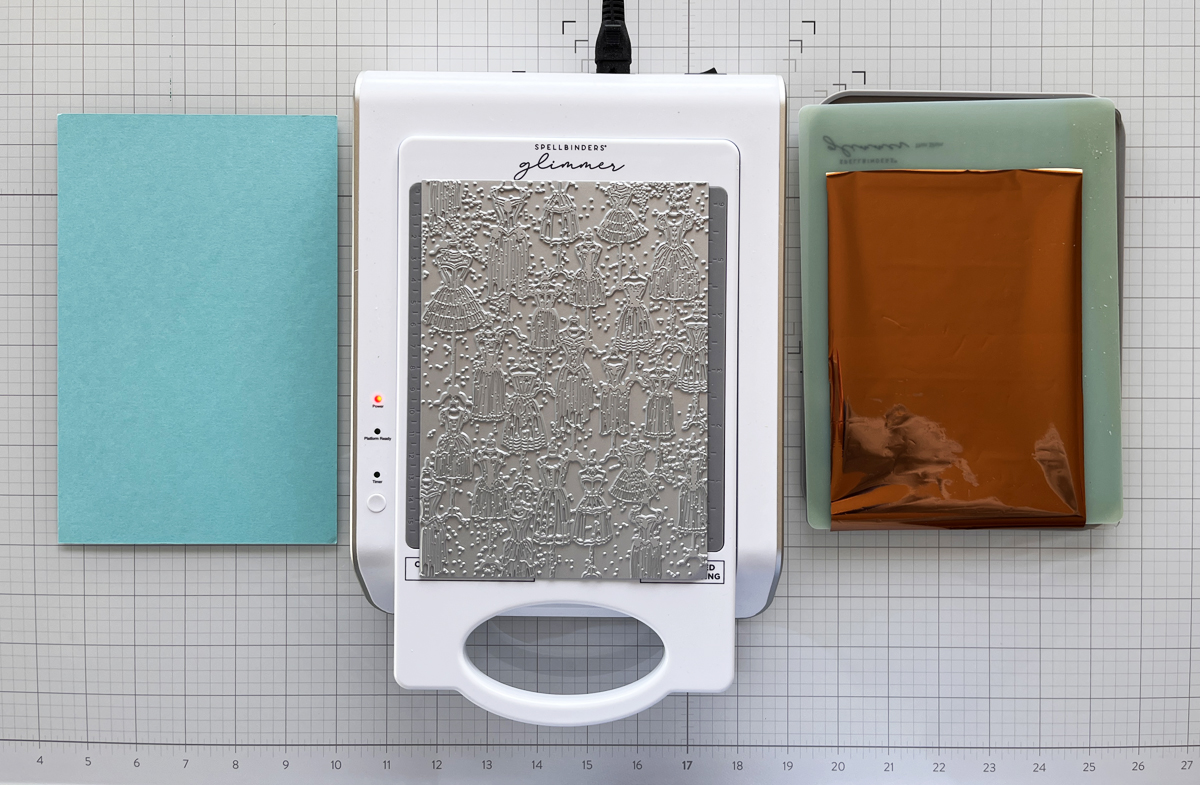 process photo of glimmer hot foil set-up on my craft mat with copper foil, Glimmer System, press plate and cardstock