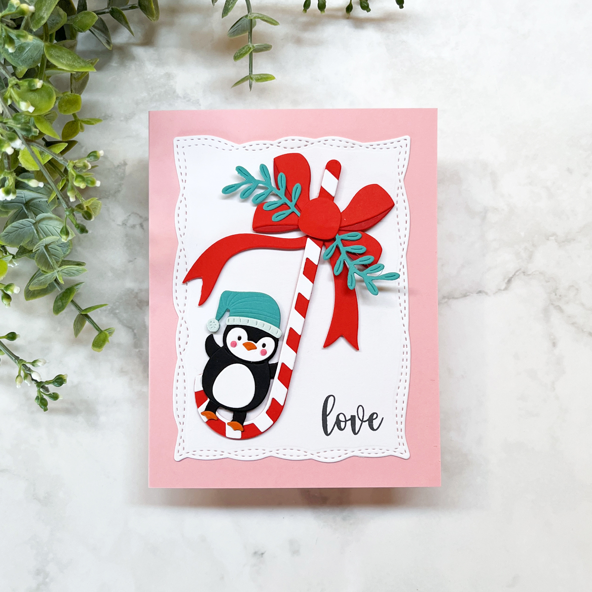 Adorable die cut Christmas Card with a penguin swinging on a candy can in pink, red and teal.