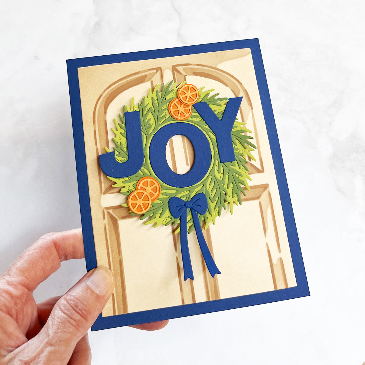 Handmade card with stenciled front door with a die cut wreath and "JOY" sentiment.