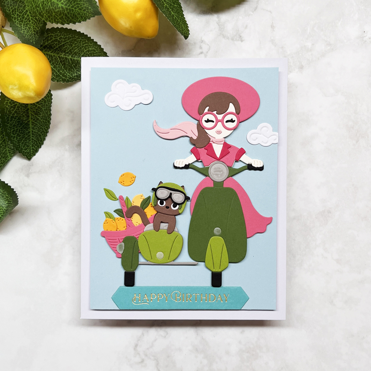 Summer scene card featuring a green scooter with sidecar, girl rider, squirrel with goggles, basket of lemons, and birthday sentiment.