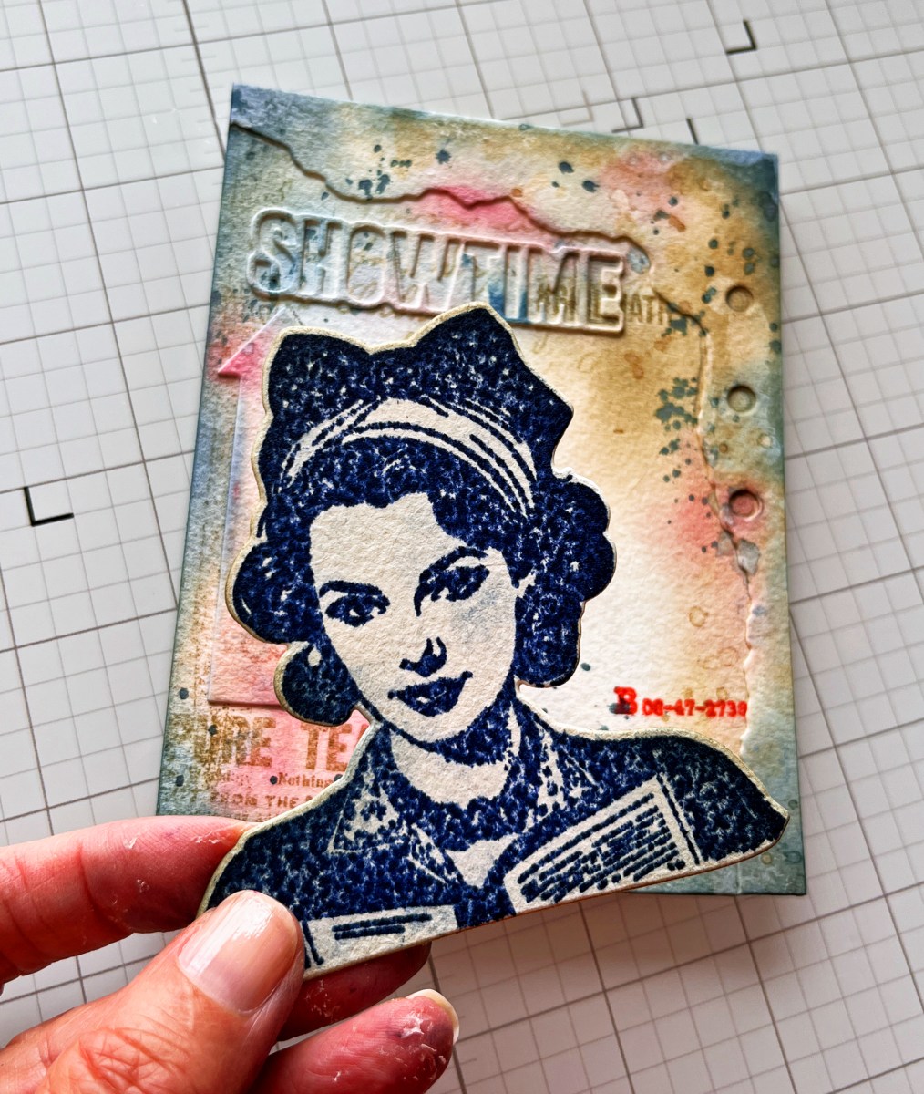 process photo of me holding my stamped and diecut mixed media focal point over the completed background, prior to assembly