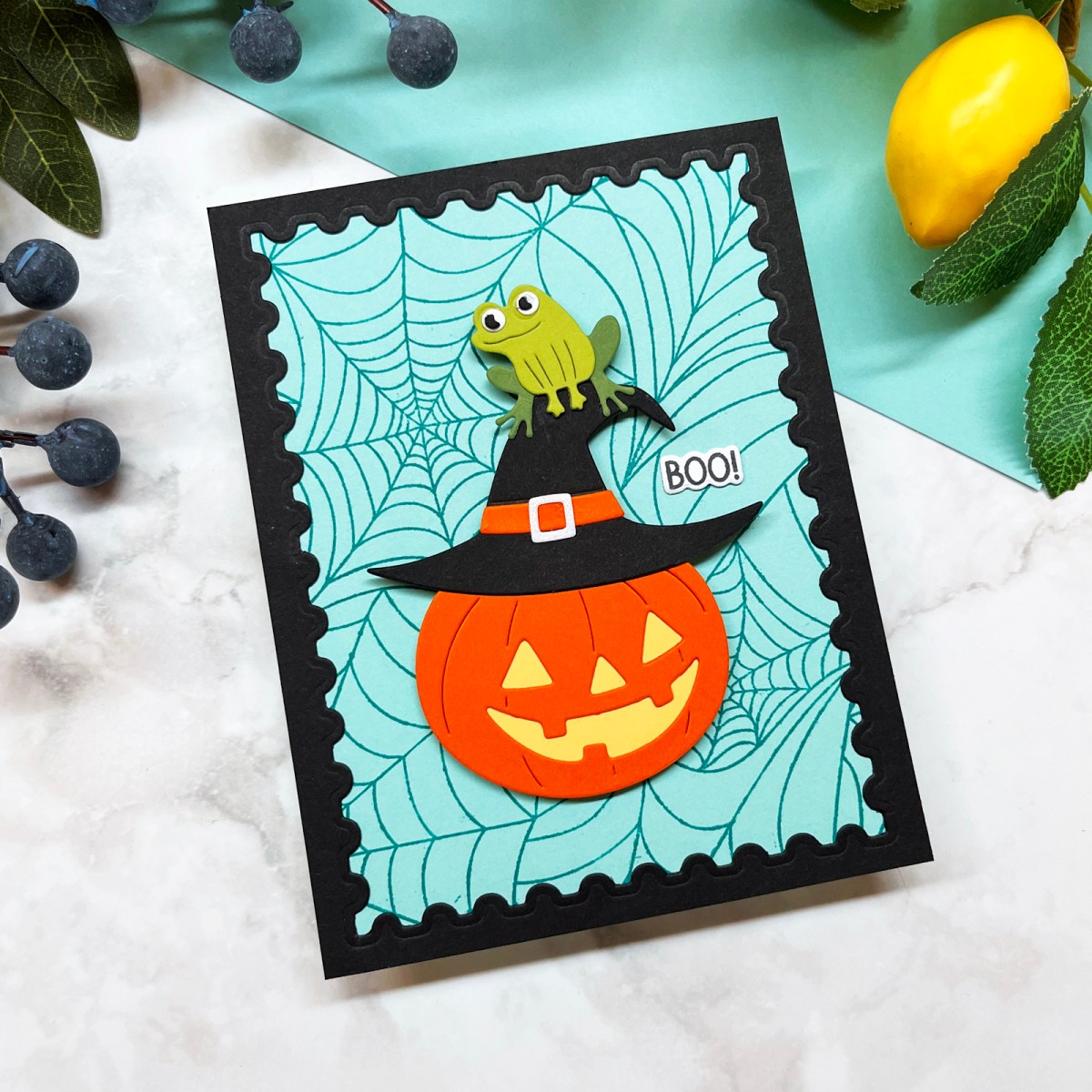 Silly Halloween card with a die-cut Jack-o-Lantern wearing a witch's hat with a frog perched on top.  Stamped spider web background and postage frame.
