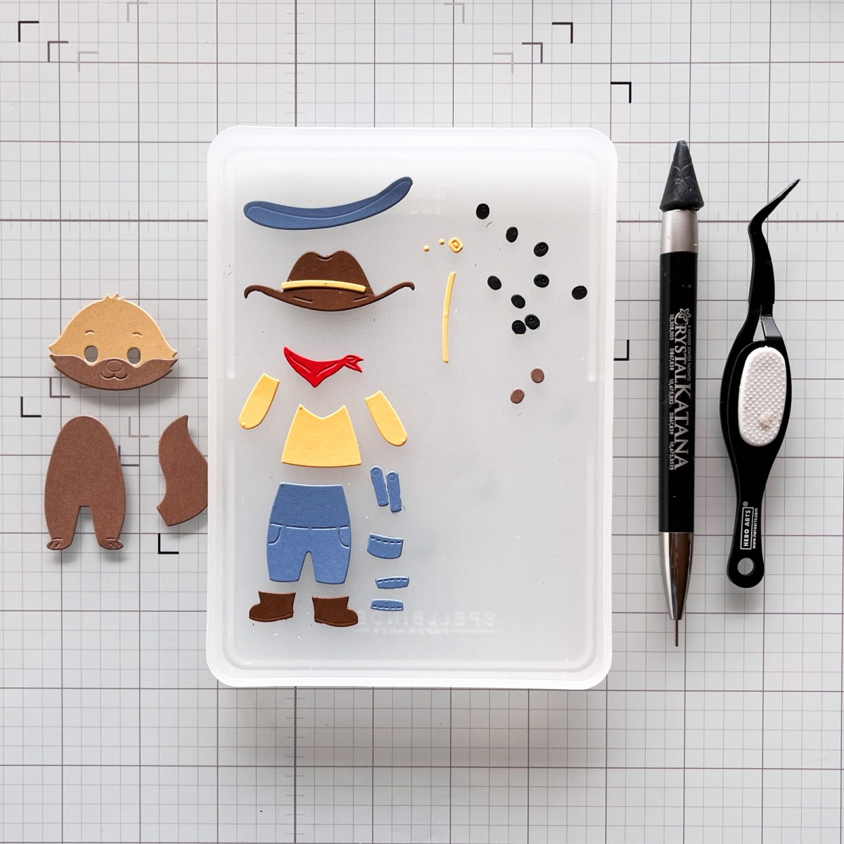 Die-cut fox and rancher clothing pieces arranged on a craft mat with additional pieces organized in CraftStax before assembly.