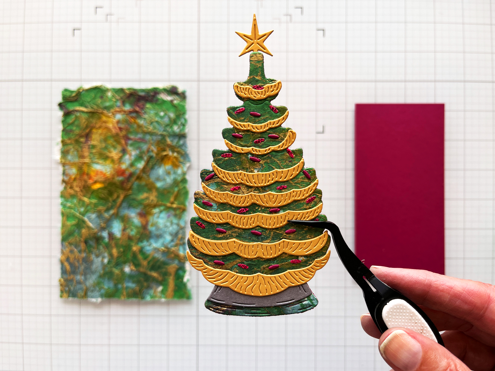 process photo of assembled die cut Christmas tree with mat and handmade paper card base in the background.  